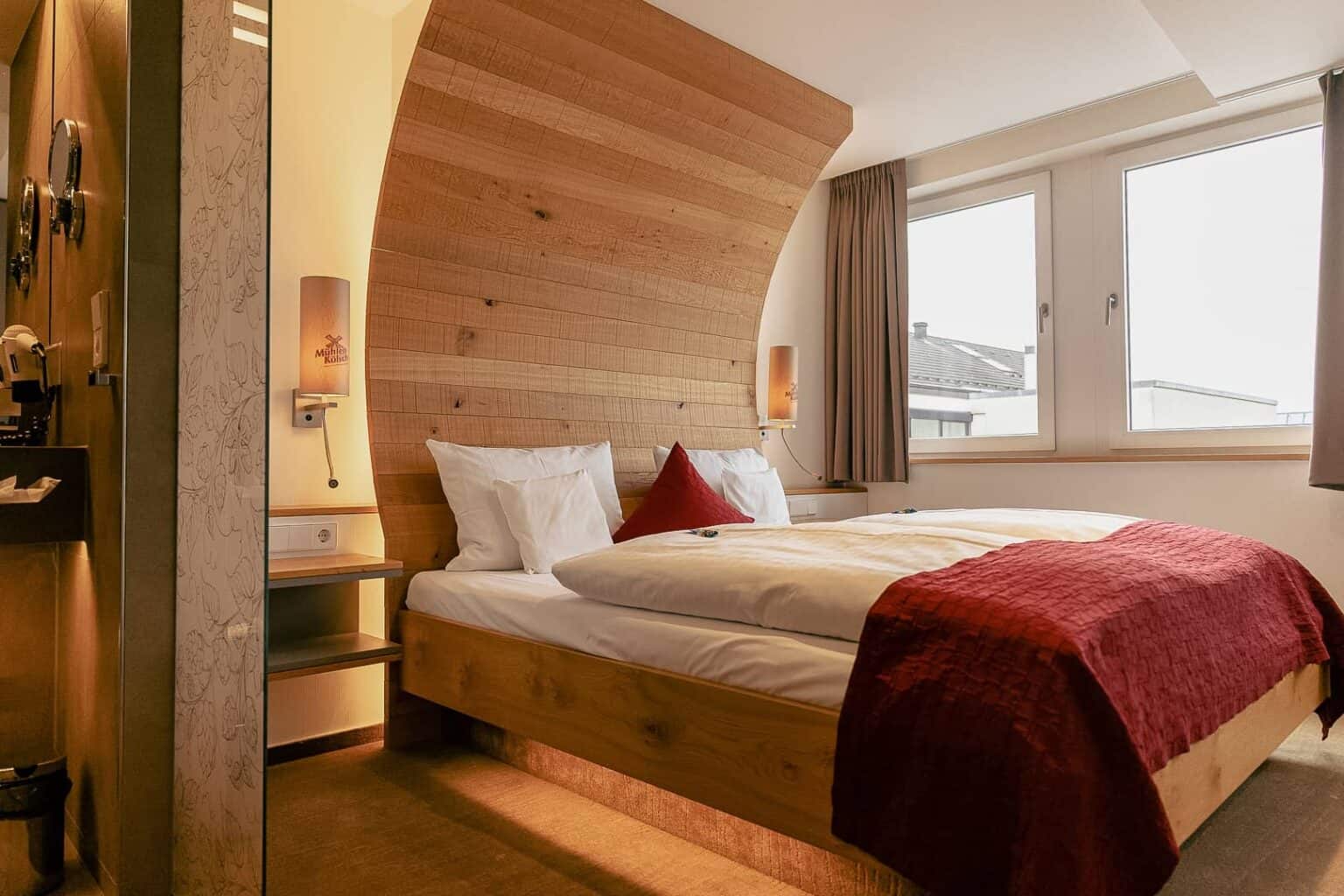 Das Foto zeigt das Hotelzimmer im Hotel zur Malzmühle mit einem Bett in Holzfassoptik